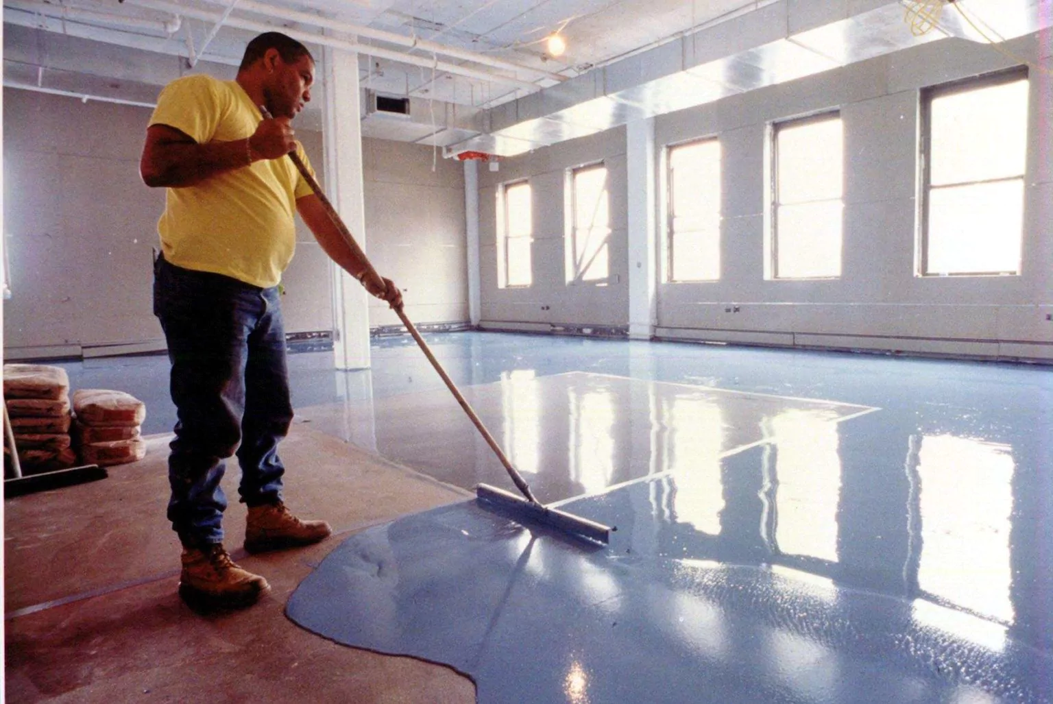 a person is applying floor finish on a garage floor with mop.