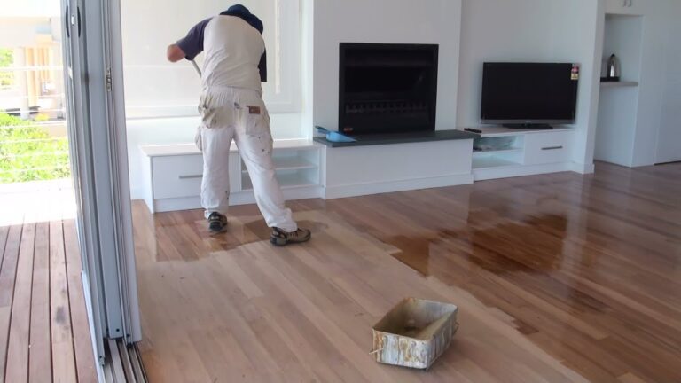 a man applying polyurethane coating on hardwood floor with mop.