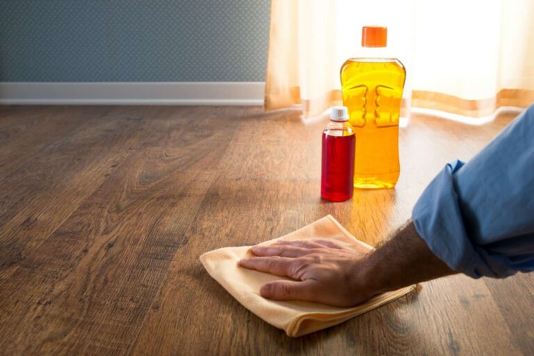 close shot of a hand waxing hardwood floor with cloth.