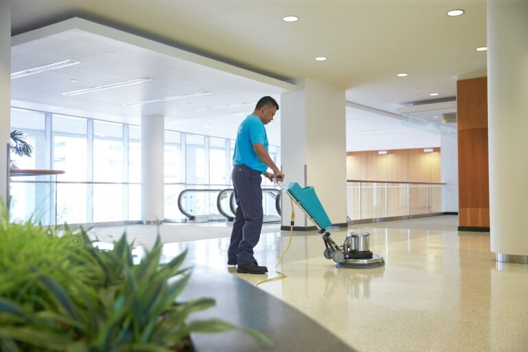 a person polishing tiles with a polishing machine in a commerical space.