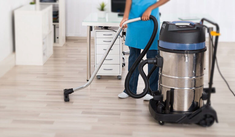 a person cleaning floor with a commercial vacuum cleaner.