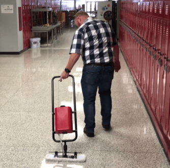 A worker coats a hallway floor with a Micro-Trak Plus